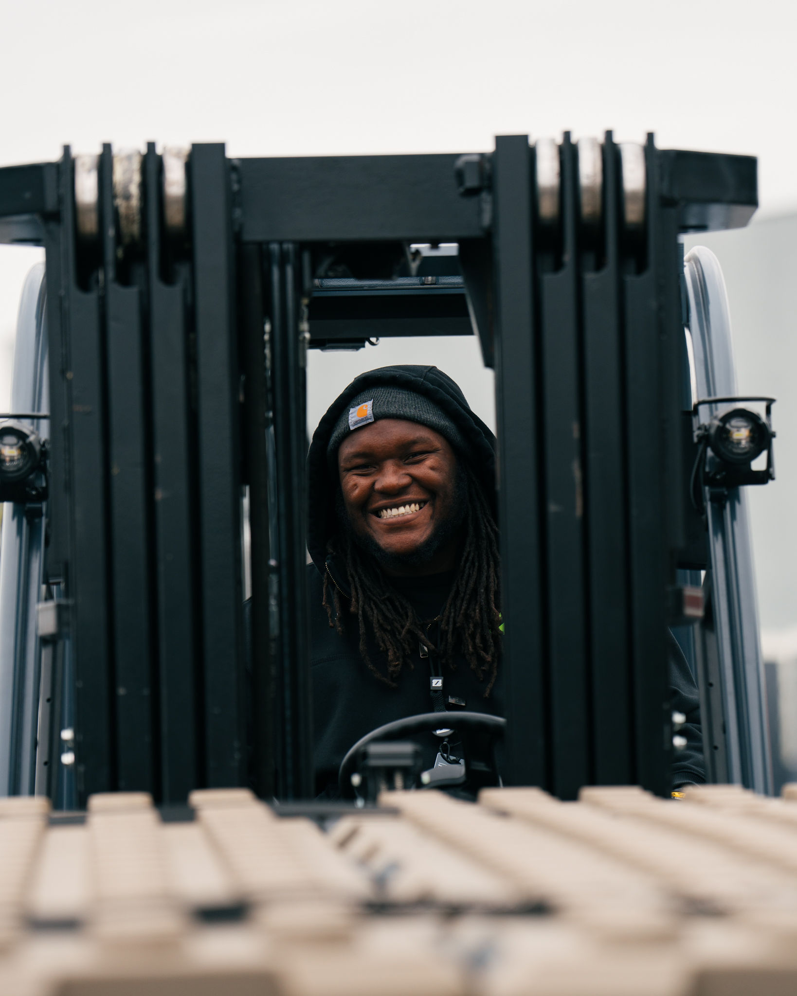 A warehouse teammate smiling from the seat of a forklift