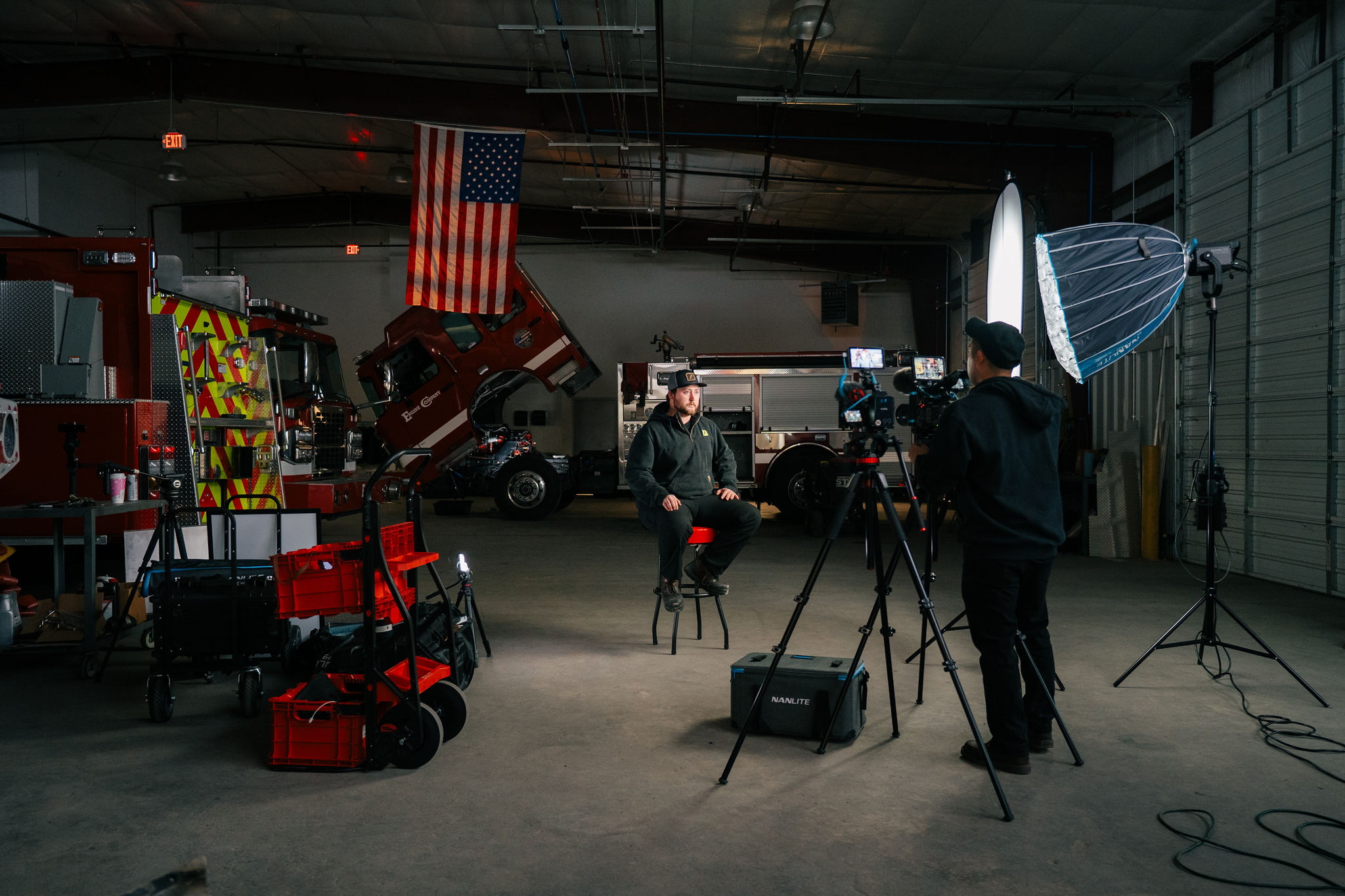 A full documentary setup in a Safe Industries service bay, lights and cameras around one chair